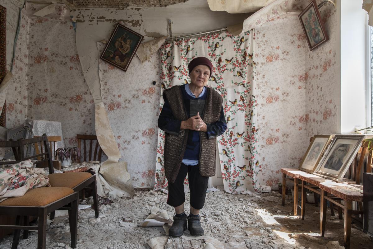 Liudmyla, 65, steht in den Ruinen ihres Hauses in Makariv im Bezirk Bucha.  © UNHCR/Andrew McConnell