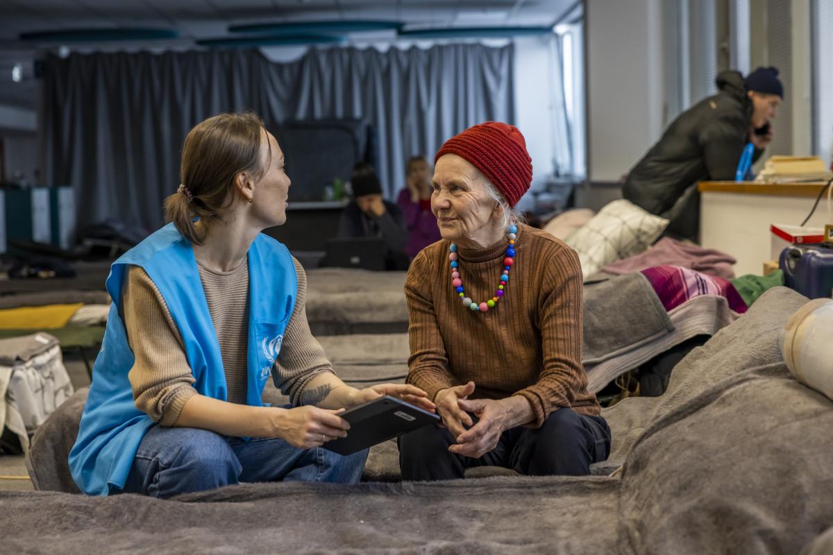 Eine UNHCR-Schutzbeauftragte spricht mit Valentina (83), die aus Kramatorsk nach Polen geflohen ist. © UNHCR/Anna Liminowicz