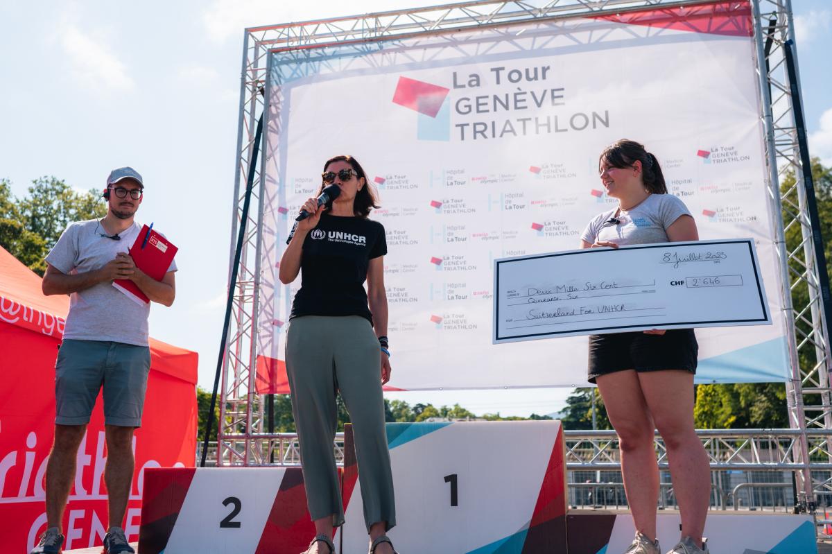 C. Davies, Executive Director of Switzerland for UNHCR, receives the symbolic award.  ©La Tour Genève Triathlon/Gabriel Madie