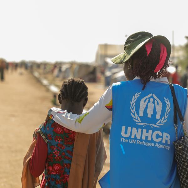 Employée du HCR soutenant un enfant réfugié déplacé par les conflicts et la vioence