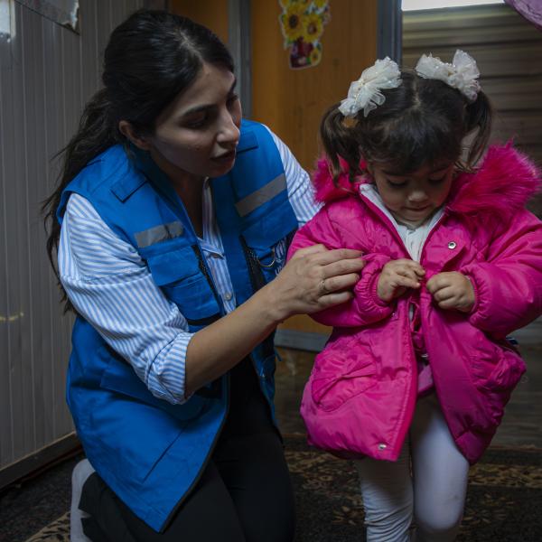 UNHCR-Mitarbeiterin mit einem syrischen Flüchtlingskind in Jordanien