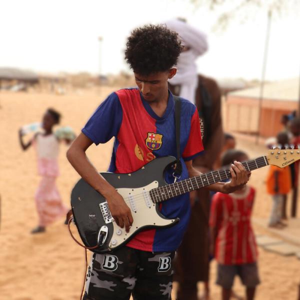 Flüchtling spielt Musik in einem Flüchtlingslager in der Wüste